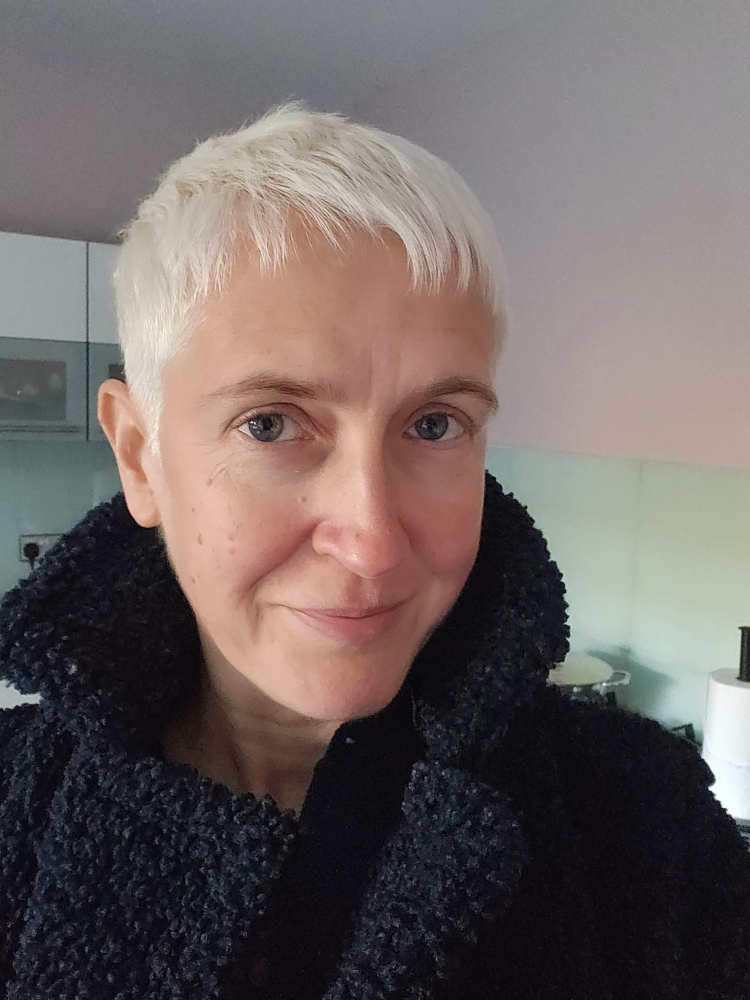 A picture of Sue Smith, a woman with short white blonde hair and a black coat
